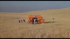 an orange van parked in the middle of a field