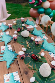 a wooden table topped with lots of paper plates and palm leaf cut outs on top of it