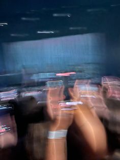 blurry image of people sitting in seats at an event with their hands up to the ceiling