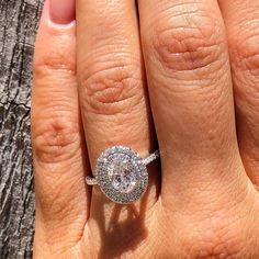 a woman's hand with a diamond ring on top of her finger and the other hand holding an engagement ring