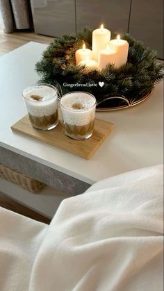 two candles are sitting on a tray next to some glasses