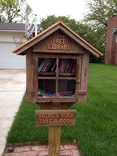 a little library with books on it in the grass