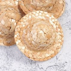 three straw hats sitting on top of a cement floor next to each other and one has a flower in the middle