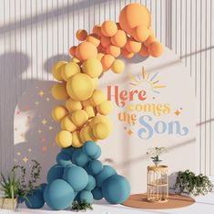 there is a balloon arch on the wall in the room that says here comes the son