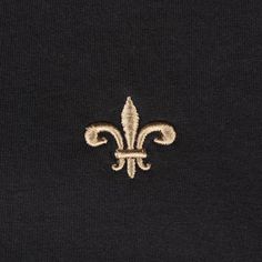 a fleur de lis embroidered on the back of a black shirt with gold trim