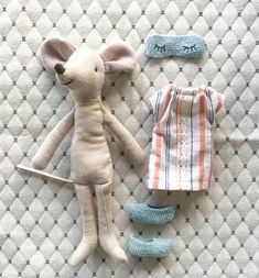 two stuffed animals laying next to each other on a quilted surface, one is white and the other is blue