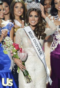 a woman in a white dress and crown waves to the crowd while standing next to other women