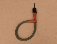 a brown and green cord connected to a cell phone on top of a tan surface