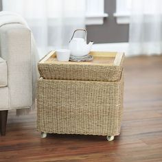 a wicker tray with a tea pot on it next to a couch