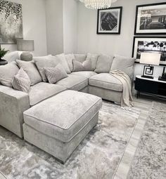 a living room with a large sectional couch and footstool in the middle of it