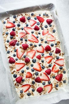 an uncooked dessert with strawberries and blueberries on top is in a pan