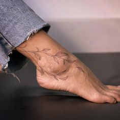 a person's foot with a tattoo on the top of it, and leaves in the bottom