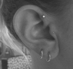 black and white photograph of woman's ear with two small hoops on it