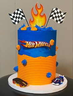 a birthday cake with hot wheels on top and flames in the background, sitting on a table