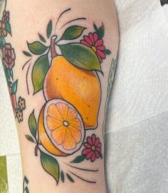 an orange with leaves and flowers around it on the leg, next to a flower