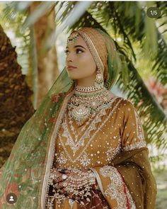 a woman in a bridal outfit standing under a tree