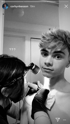 a young man getting his hair cut by a woman in front of a mirror with an electric blow dryer