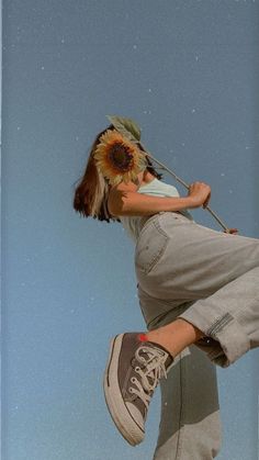 a person jumping in the air on a skateboard with a sunflower attached to their head