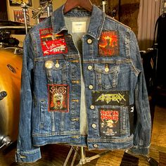 a denim jacket with patches on it sitting on a stand in front of a motorcycle