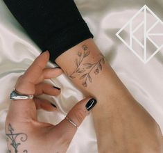 a woman's hand with a flower tattoo on her left wrist and the other arm