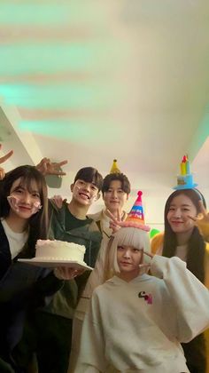 a group of people standing around each other with a cake in front of their faces