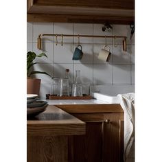 pots and pans are hanging on the wall above the sink in this small kitchen