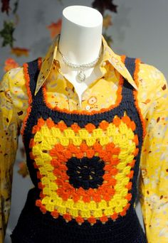 a mannequin wearing an orange, yellow and black crochet top