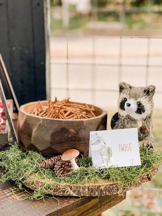 a small raccoon sitting on top of a wooden table next to a bowl of food