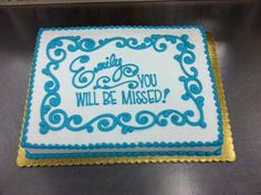 a cake that is sitting on top of a metal surface with words written in blue and gold