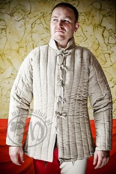 Arming cloth worn under chain mail. The gambeson is made up of three layers: 1. Outer layer - linen or leather 2. Filling - 100% cotton 3. Lining - linen This gambeson is traditionally styled using medieval iconography and has also been developed to be practical in battle. It provides excellent freedom of movement as well as a high level of protection. Freedom of movement has been achieved by varying the fill layers in different parts of the garment. Thus, the trunk has eight layers, the sleeves Fitted Medieval Outerwear For Fantasy Events, Medieval Gambeson, Pirate Garb, Medieval Archery, Wool Gifts, Linen Layers, Medieval Clothing, Chain Mail, 15th Century