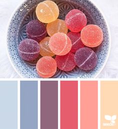 a bowl filled with candies next to a color swatch in shades of pink, orange and blue