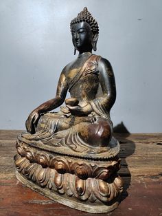 a buddha statue sitting on top of a wooden table