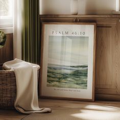 a framed poster on the floor next to a basket with a cloth draped over it