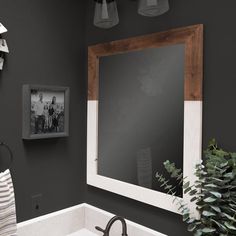 a bathroom sink sitting under a mirror next to a potted plant and light fixture