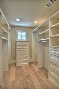 an image of a walk in closet with white shelves and drawers on the bottom shelf