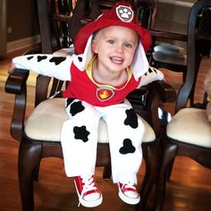 a little boy in a costume sitting on a chair