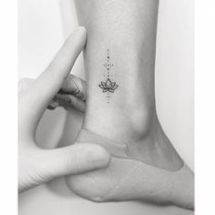 a woman's foot with a small lotus tattoo on the left side of her ankle