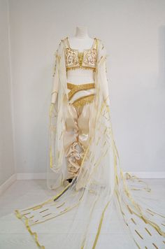 a white and gold costume on display in front of a white wall with yellow streamers