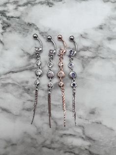 three pairs of dangling earrings on a marble surface