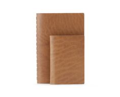 two brown leather notebooks sitting next to each other on a white surface, one is empty