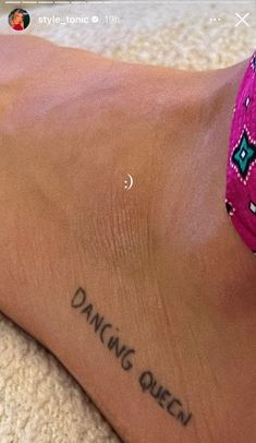 a woman's foot with the words dancing queen tattooed on her left leg and an arrow in the middle