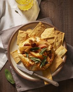 a white plate topped with nachos and fruit on top of a wooden table