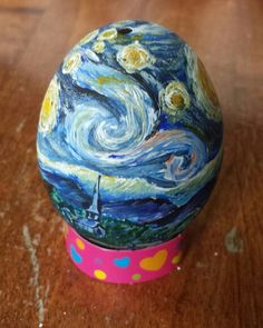 a painted rock sitting on top of a wooden table next to a pink container with polka dots