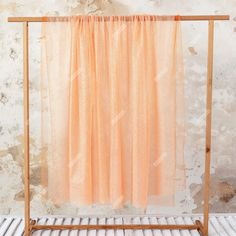 an orange sheer curtain hanging on a clothes rack