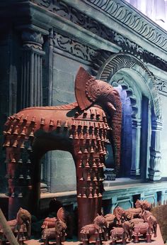 an elephant statue in front of a building with many elephants around it and people looking at it