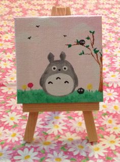 an easel with a painting of a cartoon character on it sitting on a flowery surface