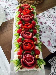 a long table with red flowers and green leaves on it, along with other decorations