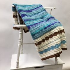 a crocheted blanket sitting on top of a white chair