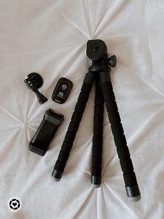 a tripod and camera sitting on top of a white bed next to other items