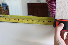 a person holding a tape measure in front of a wall with a mirror behind them